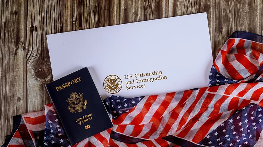 A United States passport and a USCIS envelope resting on an American flag