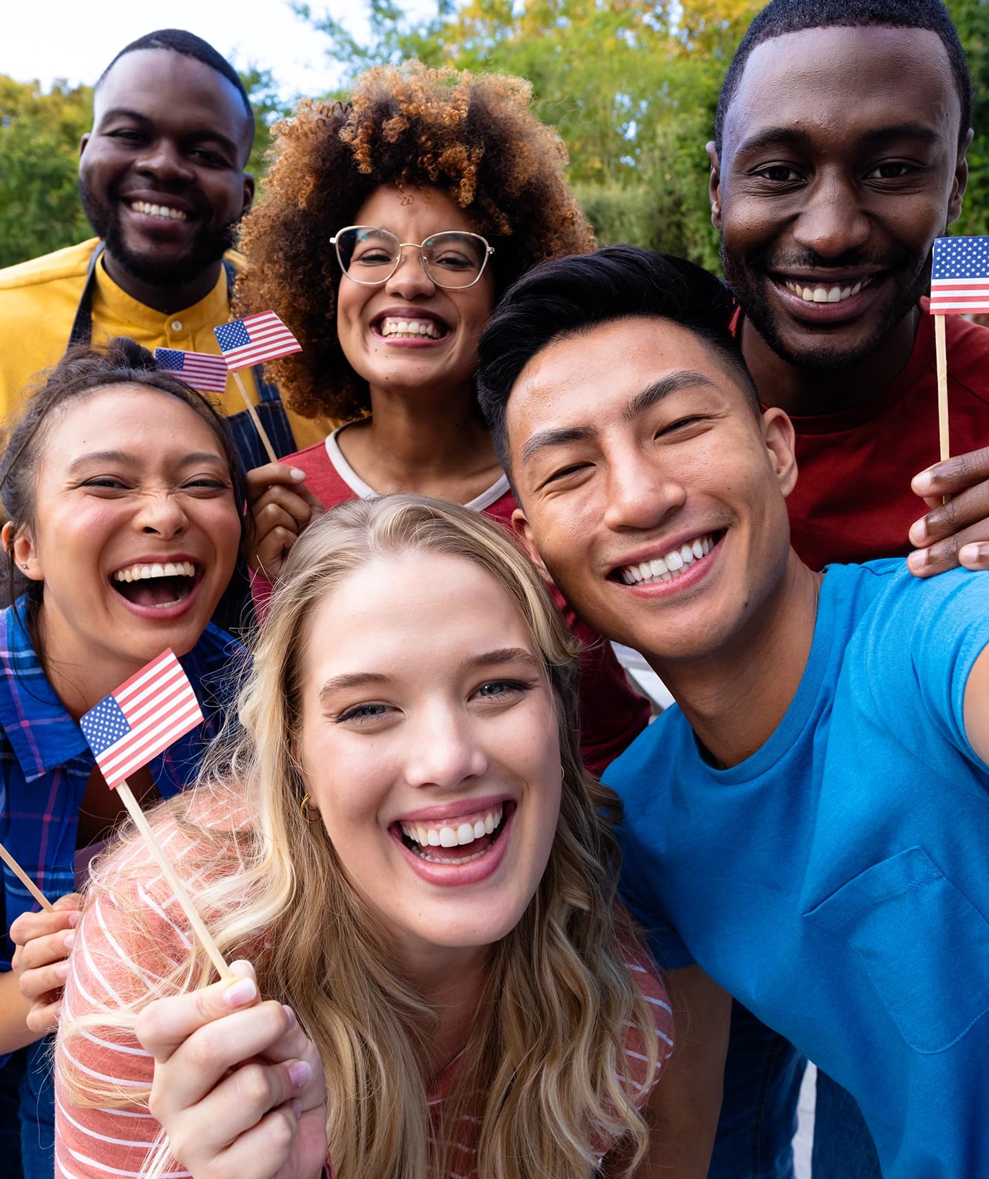 A group of people celebrating together, holding small United States flags